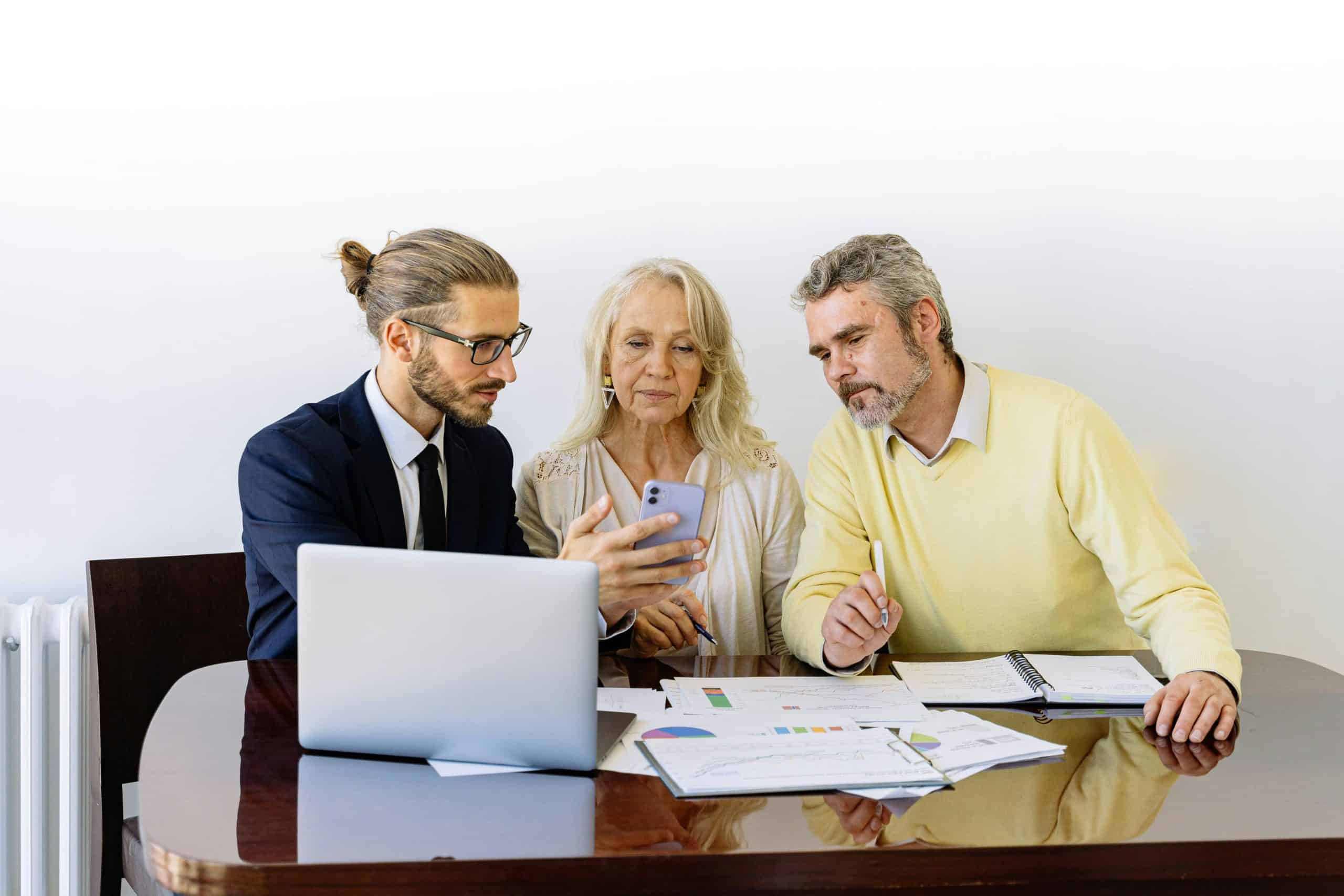 Insurance Leads And Lists Three individuals collaborating on financial documents during a business meeting.